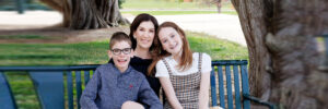 Founder of All for Kids Home Health Colorado poses with her son and daughter at a park bench