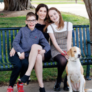 founder of All for Kids Home Health poses with her son, daughter, and dog at the park on a sunny day