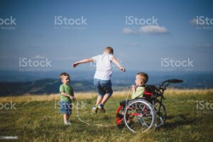 young boy in wheelchair playing with his brothers