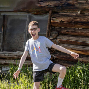 young boy balances on one leg as he gives a big smile All for Kids Home Health Colorado