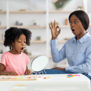 speech therapist helps child say the letter O in a classroom setting All for Kids Home Health Colorado